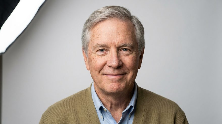 Gene — a warm, grey-haired man in an olive cardigan, smiling gently.